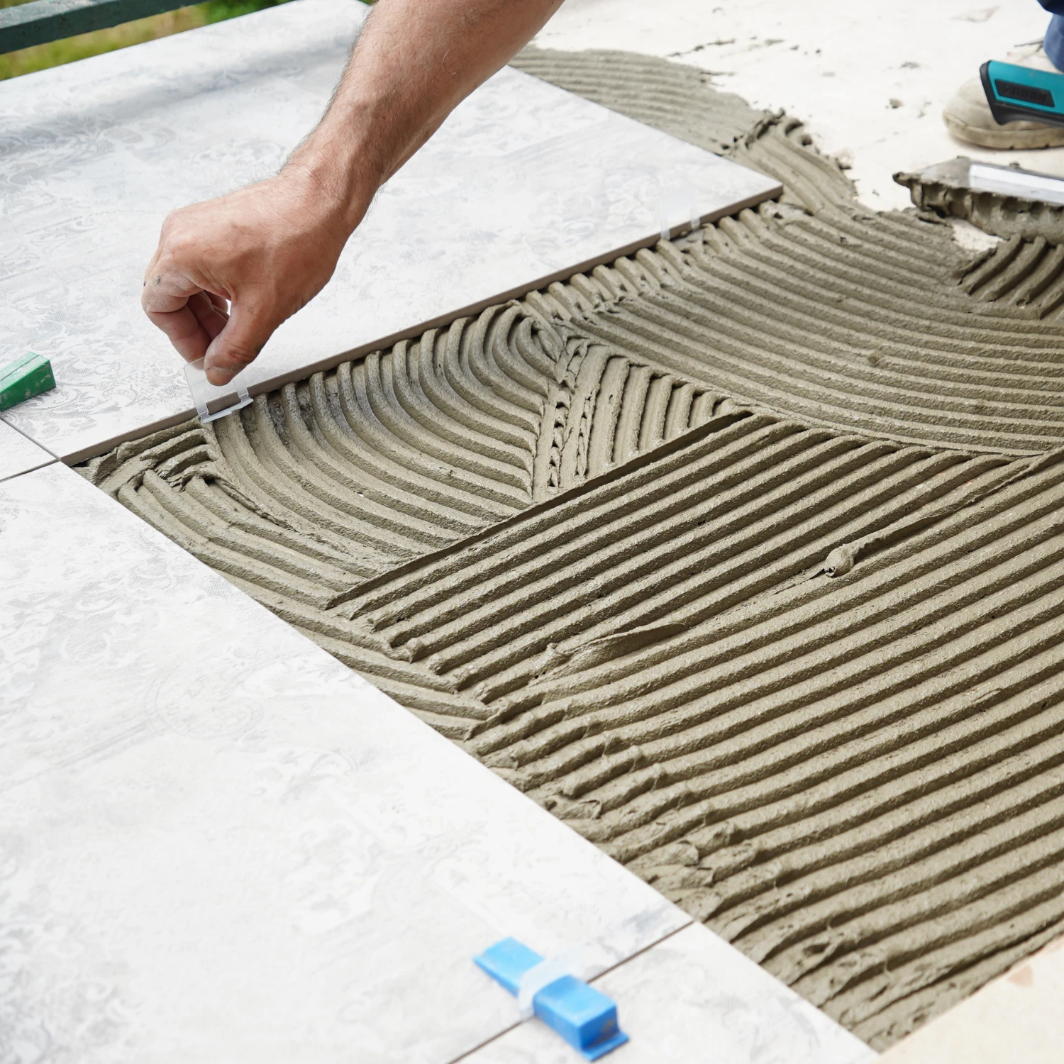 Graue Bodenfliesen werden auf dem Boden verlegt