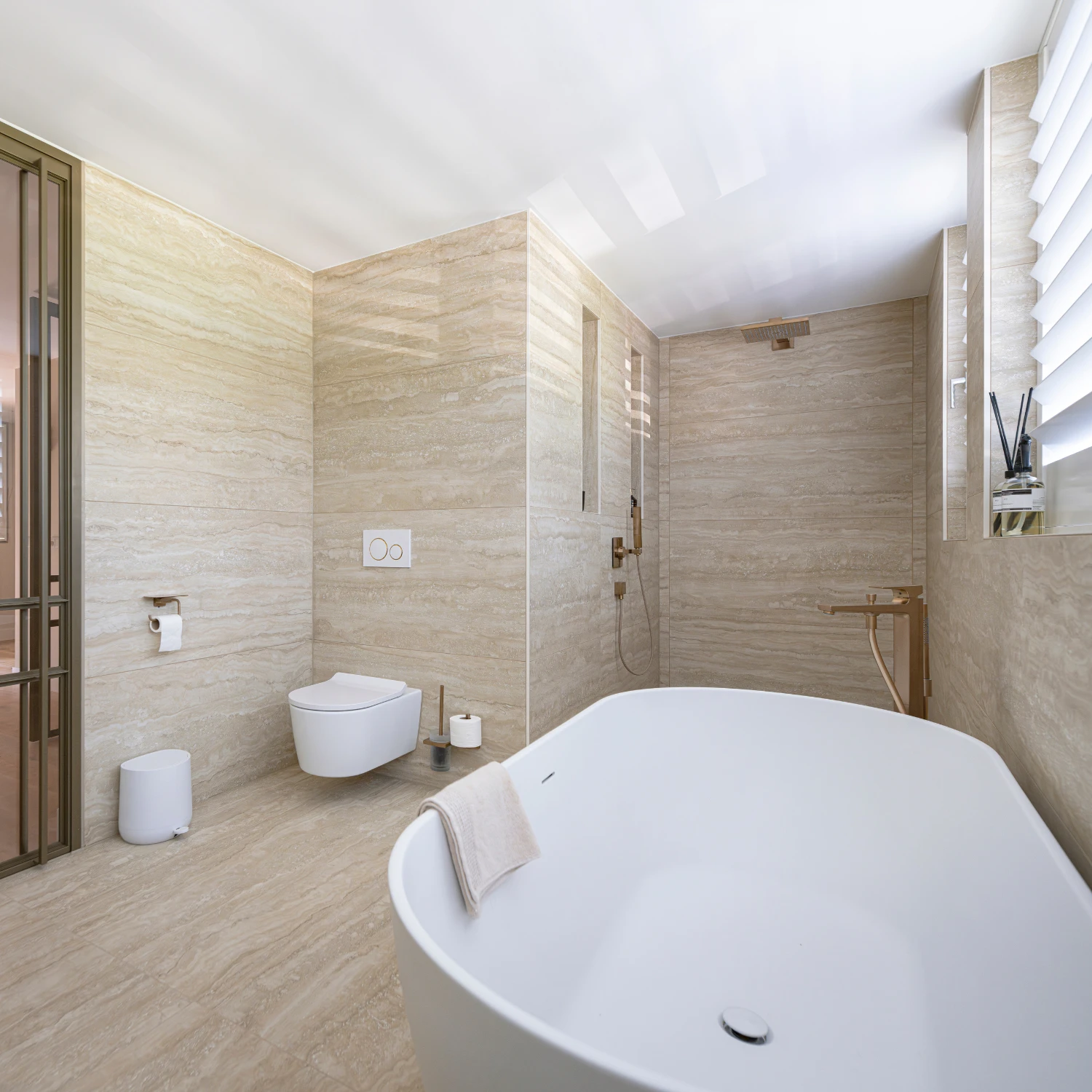 Offenes Badezimmer mit weißer Badkeramik und Travertin-Wänden