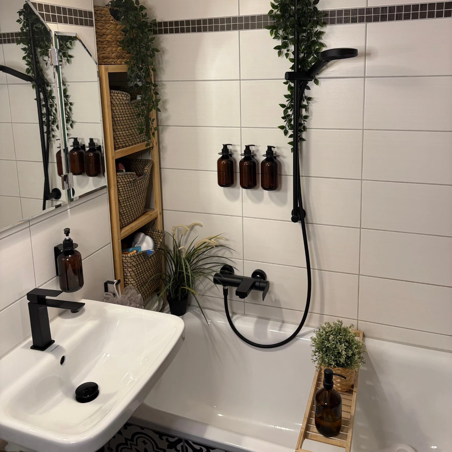 Modernes Badezimmer mit weißer Badkeramik sowie Fliesen und schwarzen Akzenten in den Armaturen.