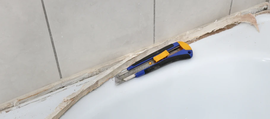 Blau-gelbes Cuttermesser neben einer alten Silikonfuge