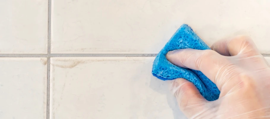 Schmutzige Fugen werden mit Hilfe eines blauen Schwamms gereinigt.